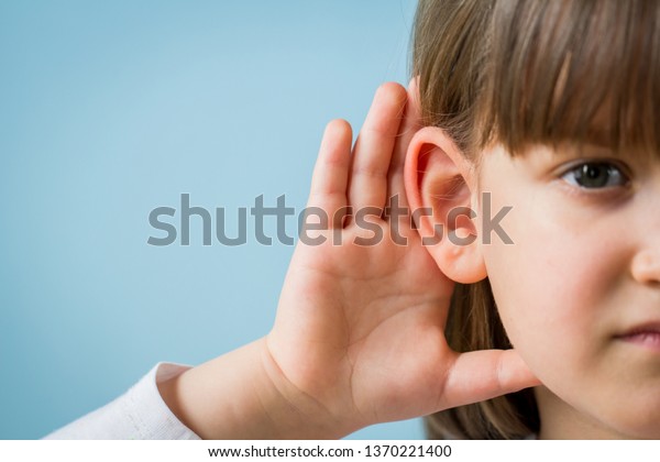 Child with hearing problem on blue background.\
Hearing loss in childhood, symptoms and treatment concept. Close\
up, copy space.