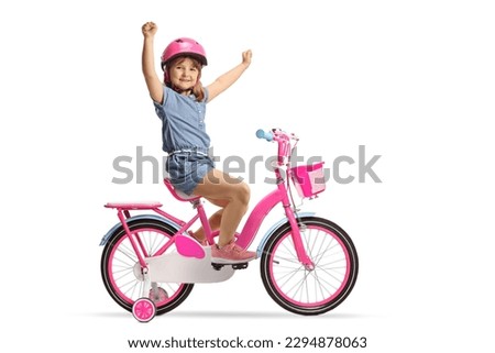 Child with a helmet riding a pink bicycle with training wheels and gesturing happiness isolated on white background