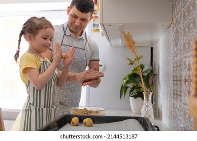 child help to father in kitchen. kid cooking food with dad. little girl, man in apron making dough, baking pie, cookies, making biscuit. family together home at stove, oven