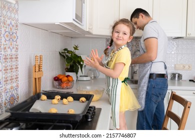 child help to father in kitchen. kid cooking food with dad. little girl, man in apron making dough, baking pie, cookies, making biscuit. family together home at stove, oven