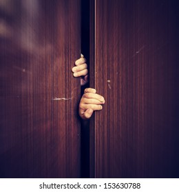 A child hides in the closet, closing the door.
