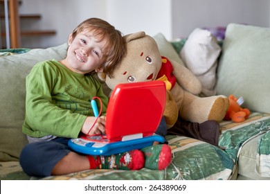 A child with his teddy bear play and learn with a toy laptop