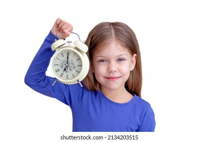 Child holding alarm with 7 o'clock on clock face, isolated on white background looking at camera waist up caucasian little girl of 5 years in blue