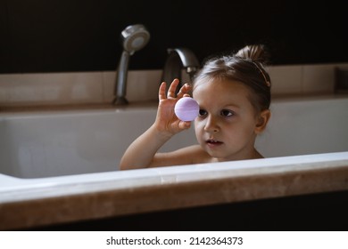 Child Holding Bath Bomb. Relaxing Hygiene Procedure For Kids. Aromatherapy And Fun At Home. Happy Toddler Girl In Bathtub Washing Herself