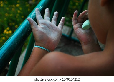 A child holding a colored chalk and looking at their hands, viewed from the back - Powered by Shutterstock