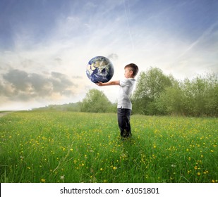 Child holding the earth on a green meadow