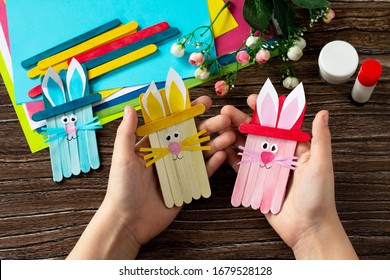 Child Is Holding Easter Bunny Toy Gift Stics Puppets On Wooden Table. Handmade. Project Of Children's Creativity, Handicrafts, Crafts For Kids.