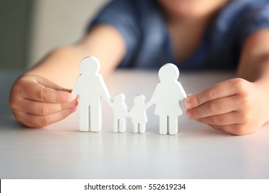 Child holding figure in shape of happy family, closeup. Adoption concept