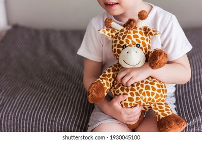 Child  Holding A Giraffe Plush Toy On A Gray Background