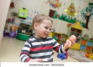 Child holding and looking at doll in kindergarten