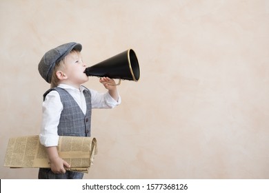 Child holding loudspeaker and newspaper. Kid shouting through vintage megaphone. Business news concept