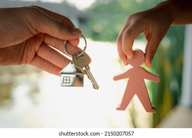 Child Holding A Model Of A Person. Picking Up House Keys And House Keyring From Dad. Concept Of Inheritance And Management