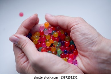 The child is holding multicolored plastic gel balls.