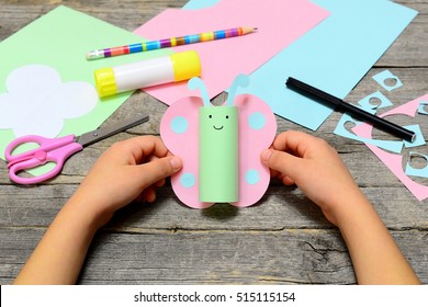 Child Holding Paper Butterfly Crafts In Hands. Child Shows A Fun Paper Crafts. Stationery On An Old Wooden Table. Preschool And Kindergarten Summer Paper Art. Easy Diy For Kids 