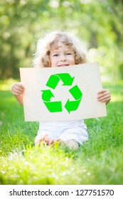 Child Holding Paper With Recycle Symbol Against Green Spring Background. Ecology Concept