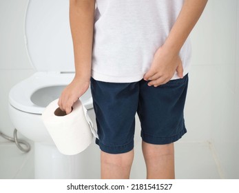 Child Holding A Paper Roll And Suffering From Diarrhea At Toilet. Health Care Concept. Closeup Photo, Blurred.