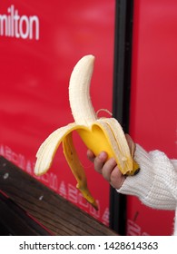 Child Holding Peeled Organic Fair Trade Banana In Front Of Red Background