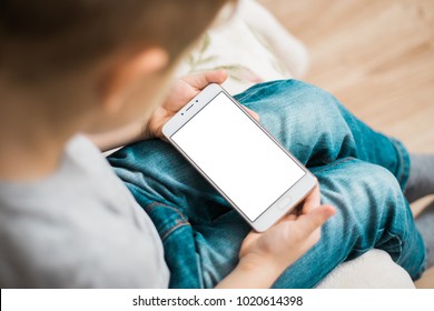 The Child Is Holding A Phone In His Hand With A White Screen For Mock Up