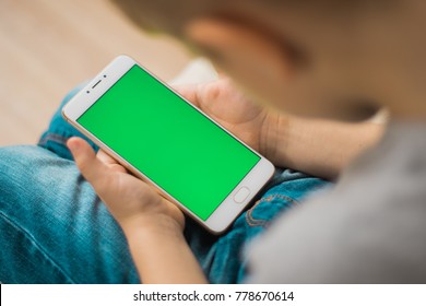 The Child Is Holding A Phone In His Hand With A Green Screen For