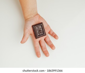 Child Holding A Piece Of Dark Chocolate Bar In Hand