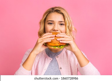 Child Holding A Piece Of Hamburger. Kid Girl Eats Fast Food. Not Helpful Food. Very Hungry Baby. Teen Girl Isolated Over Pink Background.