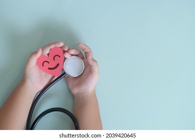 Child Holding Red Heart Paper Cut And Heart Monitor On Pastel Green Background.