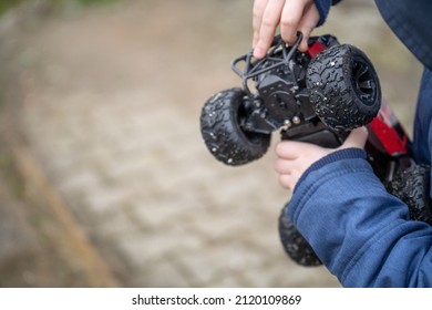 Child Holding Remote Control Car And Trying To Repair Broken Plastic Part