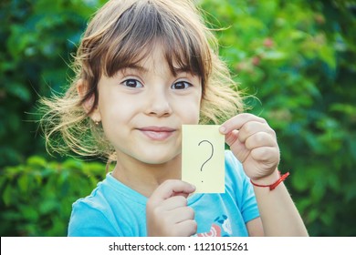 A Child Holding A Sheet Of Paper With A Question Mark. Selective Focus.