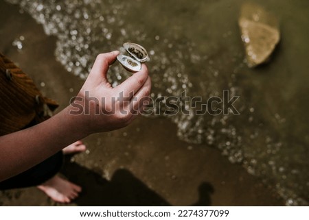 child holding shell on lakeshore