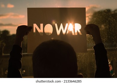 Child Holding Up Sign That Says No War Up To Apartment Window