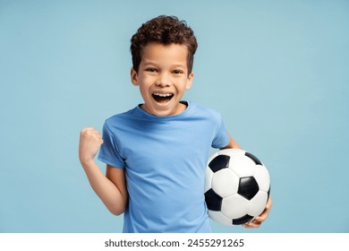 Child holding soccer football ball over isolated blue background, screaming proud, looking at camera. Playing football concept - Powered by Shutterstock