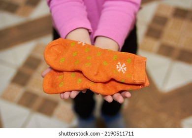 Child Is Holding Socks,little Girl Shows Socks On Her Hands, Winter Orange Socks