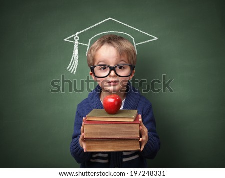 Child holding stack of books with mortar board chalk drawing on blackboard concept for university education and future aspirations
