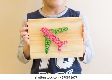 Child Holding String Art Plane