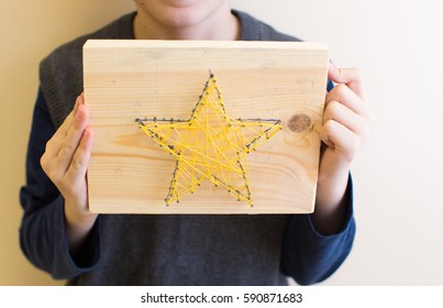 Child Holding String Art Star