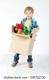 Child holding toys packed in cardboard box. Moving and growing concept