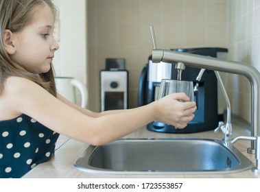 Child is holding a transparent glass. Filling cup beverage. Pouring fresh drink. Consumption of tap water contributes to the saving of water in plastic bottles and to the protection of the environment