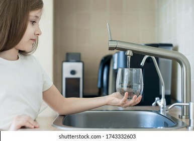 Child Is Holding A Transparent Glass. Filling Cup Beverage. Pouring Fresh Drink. Consumption Of Tap Water Contributes To The Saving Of Water In Plastic Bottles And To The Protection Of The Environment