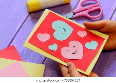 Child Is Holding A Valentines Card In His Hands. Child Is Showing A Greeting Card. Happy Valentines Day Card. Easy Paper Crafts For Kids Concept. Closeup