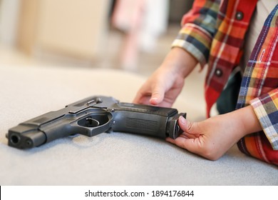 The Child Is Holding A Weapon. A Gun In The Hands Of A Boy, Danger To Life