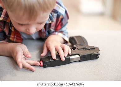 The Child Is Holding A Weapon. A Gun In The Hands Of A Boy, Danger To Life