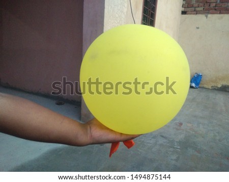 A child holding yellow coloured balloon in hand