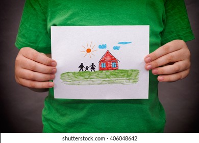 Child holds drawn house and family  Close up 