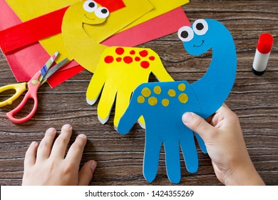 The child holds Father's day or birthday gift - card dinosaur. Handmade. Project of children's creativity, handicrafts, crafts for kids.
 - Powered by Shutterstock