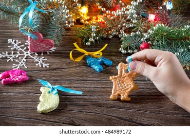 The Child Holds A Garland Of Christmas Decorations From Salt Dough. Children's Art Project, A Craft For Children.