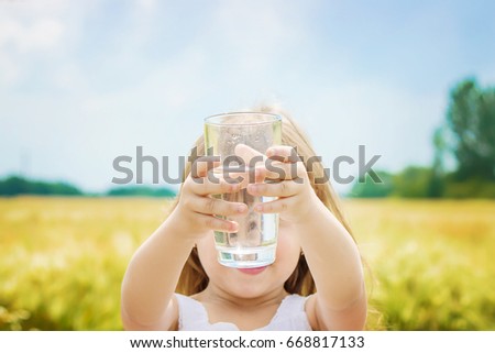 the child holds a glass of water in her hands. selective focus. 