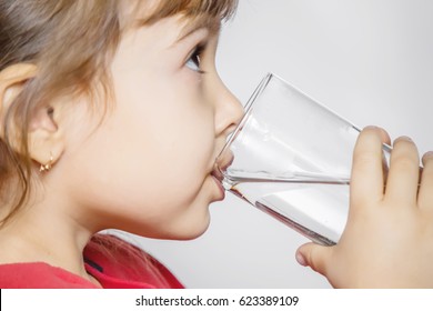 The Child Holds A Glass Of Water In His Hands. Selective Focus. 