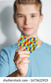 Child Holds Jigsaw Pattern Heart In His Hands. Mental Health Care Concept. World Autism Awareness Day