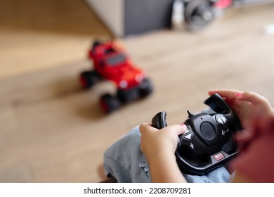 The Child Holds A Radio Control Panel From A Red Car Toy In His Hands And Controls It. Modern Toys For Children.