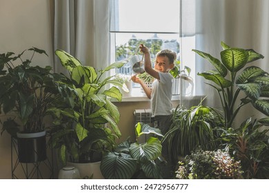 A child in home clothes waters beautiful, large indoor plants from a stylish metal watering can. Concept Care and watering of home flowers. - Powered by Shutterstock